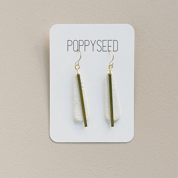 White clay and brass long teardrop earrings on a Poppyseed branded card against a beige background