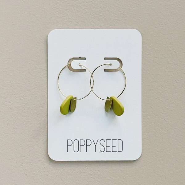 Gold hoop earrings with chartreuse clay and brass accents on a 'Poppyseed' branded card against a beige background