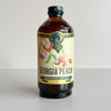 A bottle of Portland Georgia Peach Premium Beverage Concentrate syrup, featuring an amber glass bottle with a cream-colored label decorated with peach illustrations.