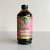 A bottle of Portland Syrup Raspberry Rhubarb Premium Beverage Concentrate, featuring a pink label with green and gold details, set against a plain light gray background.