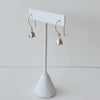 Silver flower shaped earrings on a white earring stand against a light gray background