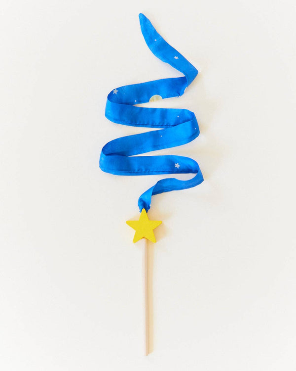 A wood wand with a yellow star at the tip sporting a long blue silk streamer against a white backdrop.