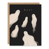 A black greeting card with five white ghost illustrations and the word 'boo!' at the top, shown with a brown kraft envelope behind it on a white background.