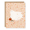 A greeting card with a whimsical illustration of a Halloween costume ghost with pumpkin trick-or-treat buket with an autumnal confetti backdrop, paired with a kraft paper envelope.