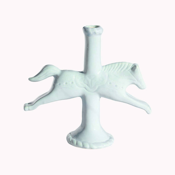 Light blue ceramic horse shaped taper candle holder against a white background.