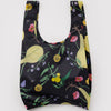 A nylon shopping bag in black with a colorful print of winter gourds and flowers on a white backdrop.