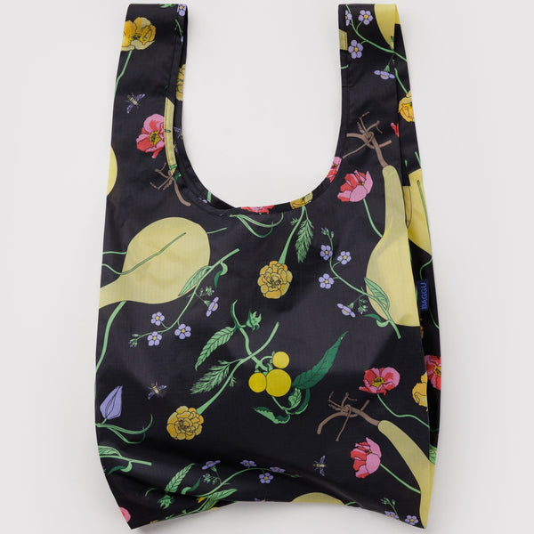 A nylon shopping bag in black with a colorful print of winter gourds and flowers on a white backdrop.
