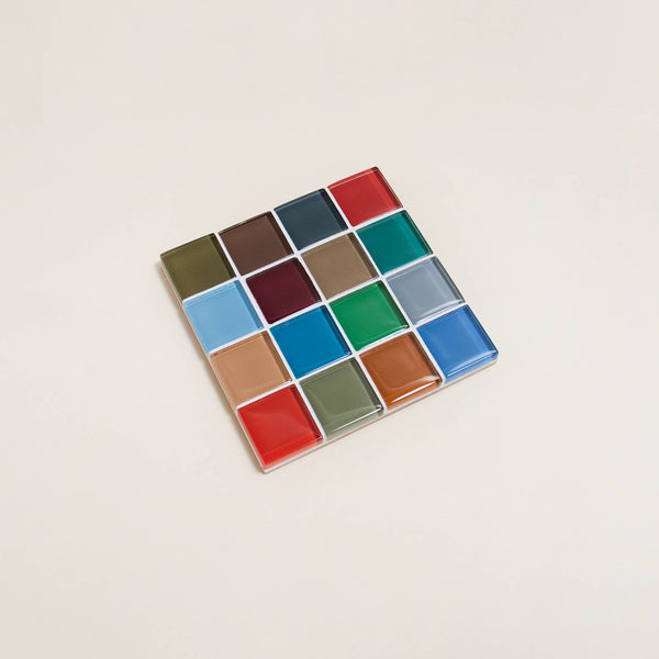 A richly colorful glass mosaic tile coaster against a neutral background.
