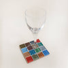A rich colorful mosaic glass coaster holding a wine glass against a neutral background.