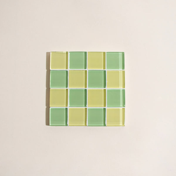 Square mosaic tile coaster with green and yellow checkered pattern on a beige background