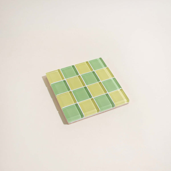 Square mosaic tile coaster with green and yellow checkered pattern on a beige background