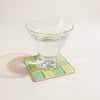 Clear glass on a green and yellow checkered coaster with a light background