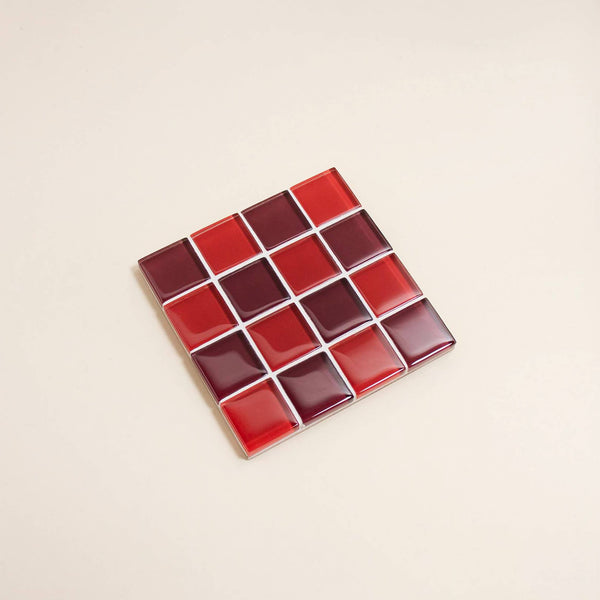 Red and dark red glass mosaic tile coaster against a neutral background.
