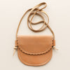Tan leather kid-sized crossbody bag with a strap on a light beige background