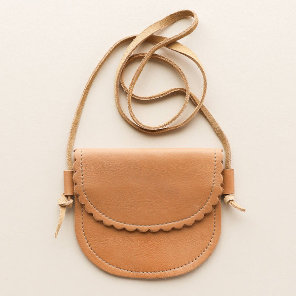 Tan leather kid-sized crossbody bag with a strap on a light beige background