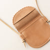Close-up of a tan leather kid-sized purse with a scalloped edge on a light background