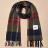 A large fringed lambswool scarf in a rich navy, olive green, red, and white tartan plaid against a neutral background.