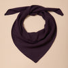 A dark purple fine knit triangle shaped scarf twisted against a neutral background. 