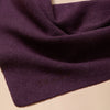 A detailed view of a fine knit dark purple scarf with matching 'tbco' branding embroidered on the edge, sitting on a neutral background.