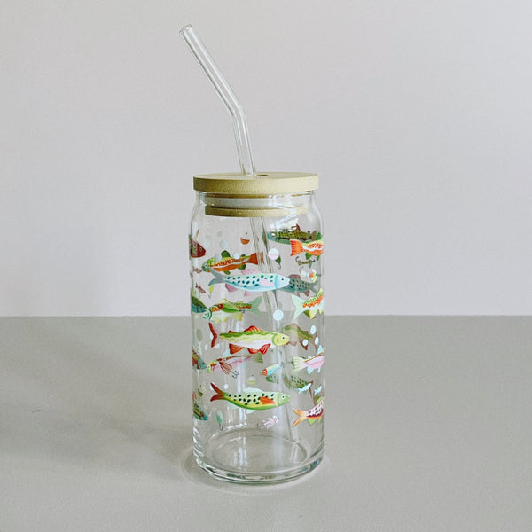 A glass travel cup with bamboo lid and glass straw. The cup is printed with a colorful fish design.