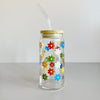 Glass travel cup featuring a colorful floral screen print. The cup has a bamboo lid and glass straw. 