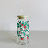 A glass travel cup with bamboo lid and glass straw. The cup is printed with a colorful strawberry floral vines design. 
