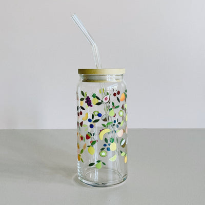 A glass travel cup with bamboo lid and glass straw. The cup is printed with a colorful array of tropical fruits. 