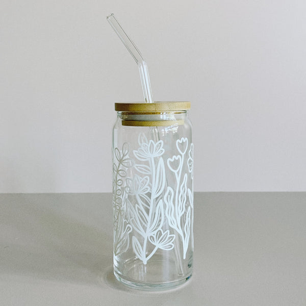 A glass travel cup with bamboo lid and glass straw. The cup is printed in a whimsical white floral design.