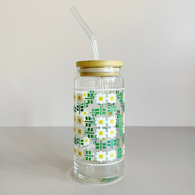 A glass travel mug featuring a white, yellow, and green daisy quilt print. The cup includes a bamboo lid and glass straw. 