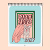 A spiral-bound 2027 wall calendar featuring a cute cartoon dog illustration and the words 'GOOD DOGS 2027' on a light blue background, shown against a soft peach backdrop.