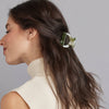 A person with a half ponytail held back by a small arch hair claw against a grey background.