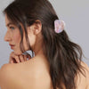 Woman with a half ponytail wearing a hair clip against a gray background
