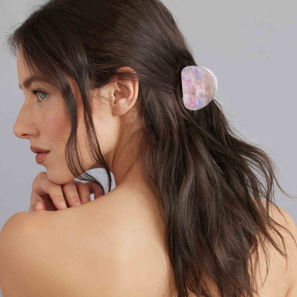 Woman with a half ponytail wearing a hair clip against a gray background
