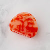 Orange and white marbled oblong hair claw on a light gray marble background