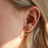 Close-up of an ear wearing gold hoop earrings with a soft focus on hair and skin.