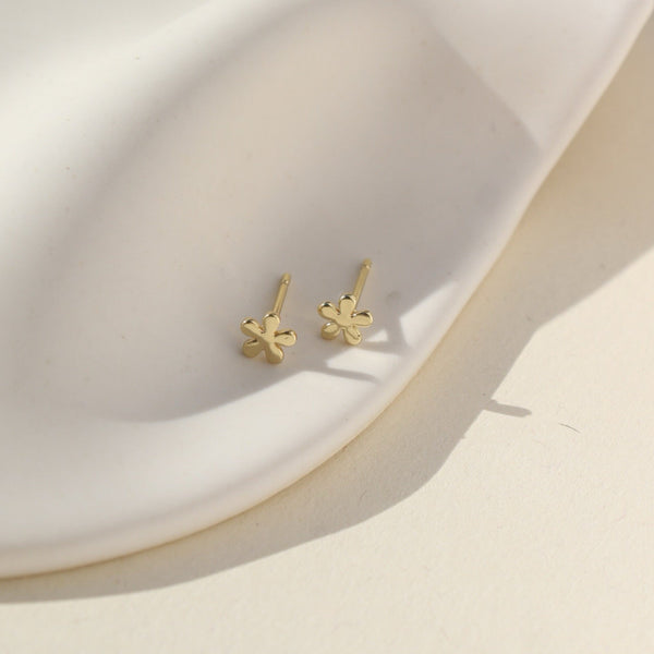 Gold flower-shaped earrings on a white surface