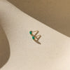 Gold earrings with emerald gemstones on a beige surface