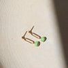 Gold earrings with turquoise beads on a beige background