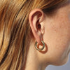 Person wearing a chunky gold hoop earring.