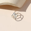 A sterling silver double banded ring on a shadowy neutral background.