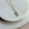 Gold necklace with a bow pendant on a light marble surface