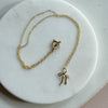 Gold necklace with a bow pendant on a marble surface