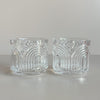 A set of two crystal lowball glasses featuring an Art Deco inspired arc design against a neutral backdrop.