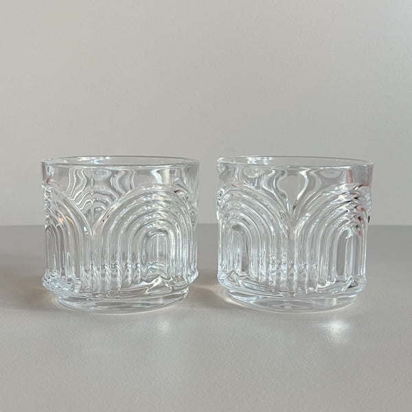 A set of two crystal lowball glasses featuring an Art Deco inspired arc design against a neutral backdrop.