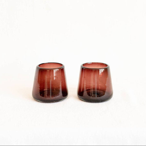Two amethyst handblown glass tumblers on a white background