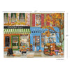 Illustrated jigsaw puzzle of a quaint town street with a General Store and Cafe, featuring pumpkins and autumn decorations. The completed puzzle is set against a white background showing dimensions.