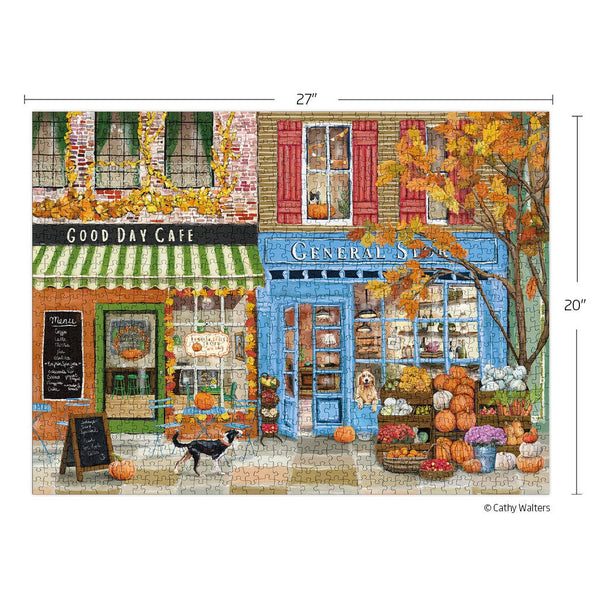 Illustrated jigsaw puzzle of a quaint town street with a General Store and Cafe, featuring pumpkins and autumn decorations. The completed puzzle is set against a white background showing dimensions.