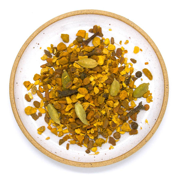 A plate filled with a golden milk loose leaf tea blend, sitting on a white background. 