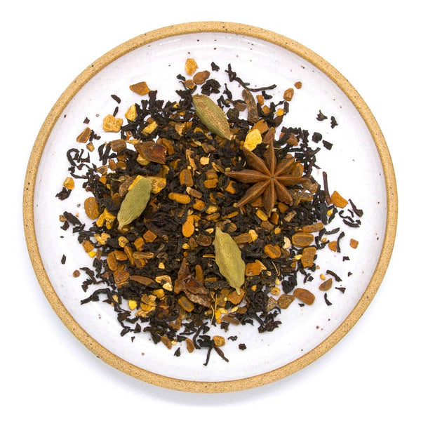 A loose leaf blend of black tea house chai on a white ceramic plate against a white surface.