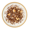 A top-down view of loose-leaf herbal tea  on a round speckled ceramic plate with a beige rim, set against a solid white background.
